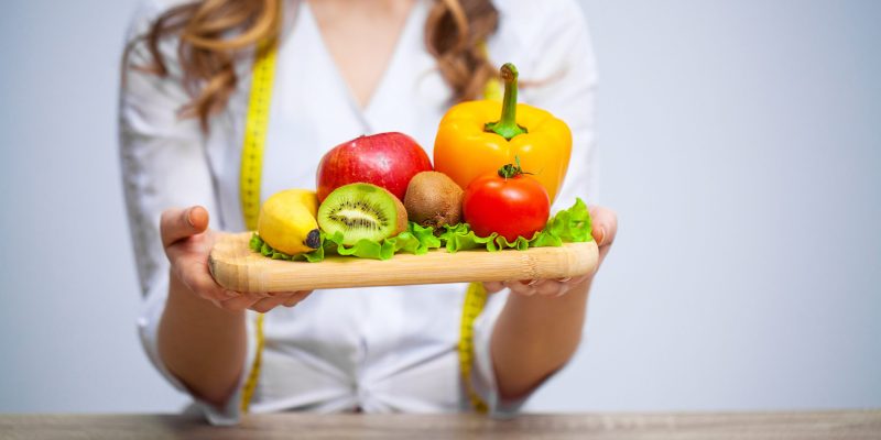 Doctor Nutritionist holding fresh fruits and vegetables for healthy diet.